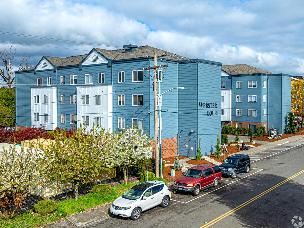 a city street with cars parked in front of an apartment building