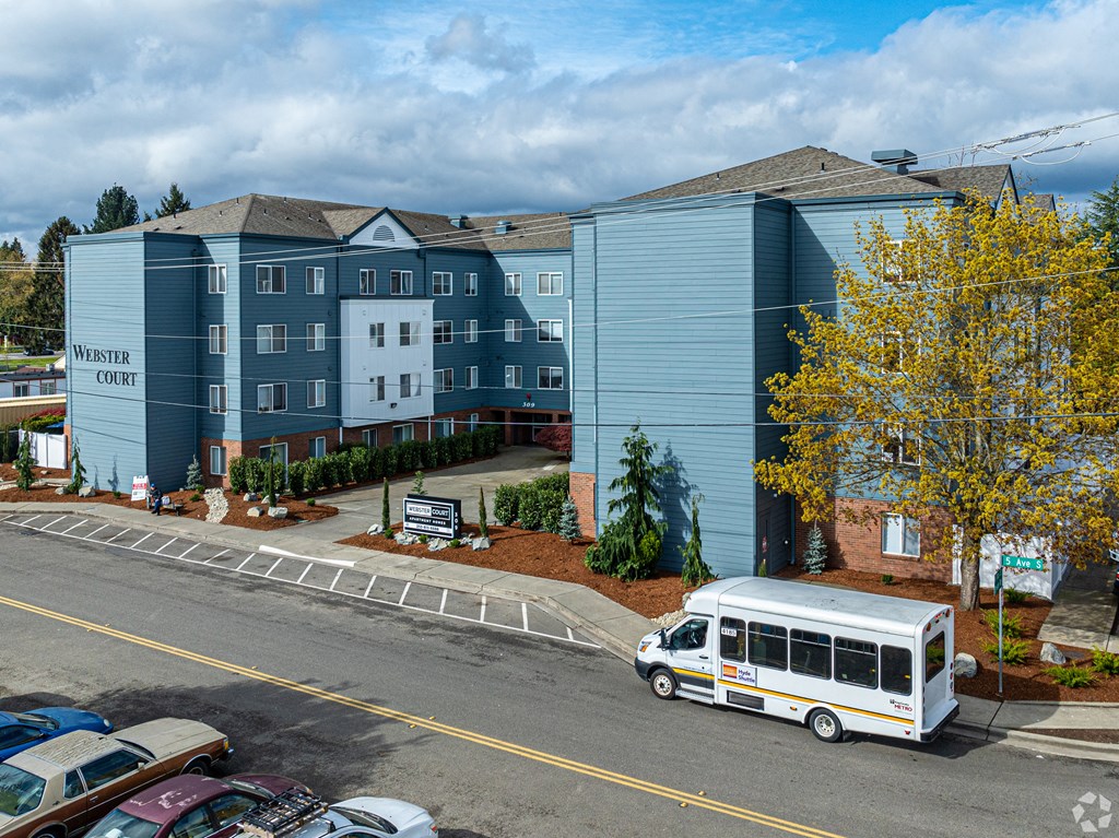 a white bus parked in front of an apartment building