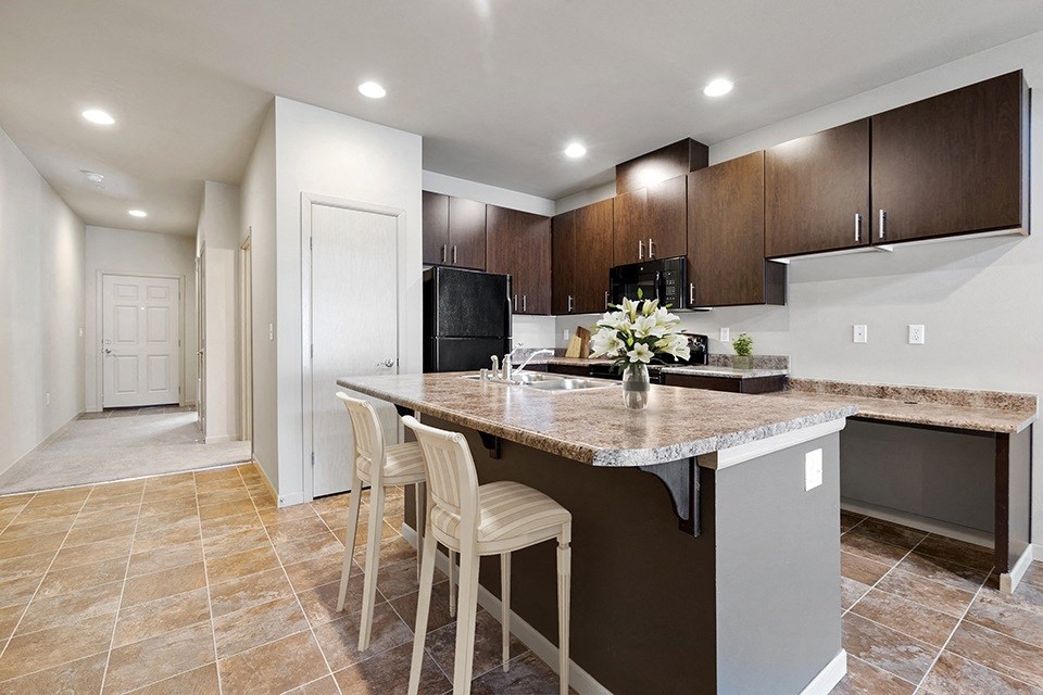 Olympia WA Apartments - Yauger Park Villas - Modern Kitchen with Tiled Flooring, Granite Countertops, and Dark Wood-Style Cabinets