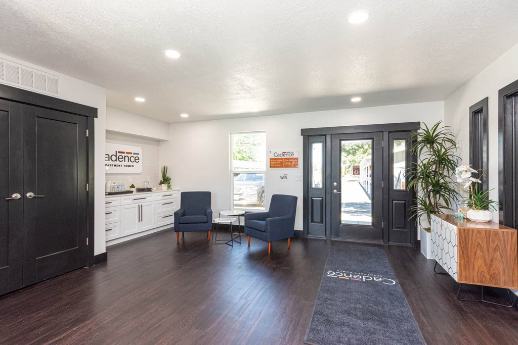 a living room with two chairs and a table and a door at Cadence Apartments, Roy Utah