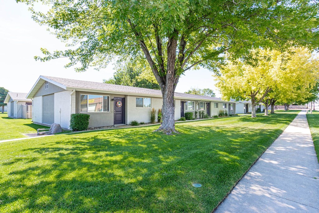 a row of houses in a yard with grass and trees at Cadence Apartments, Roy