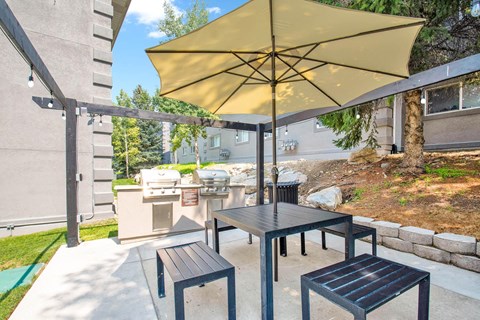 a patio with a table and chairs with an umbrella at Mountain Run Apartments, 84058