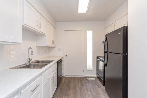 a kitchen with white cabinets and a black refrigerator