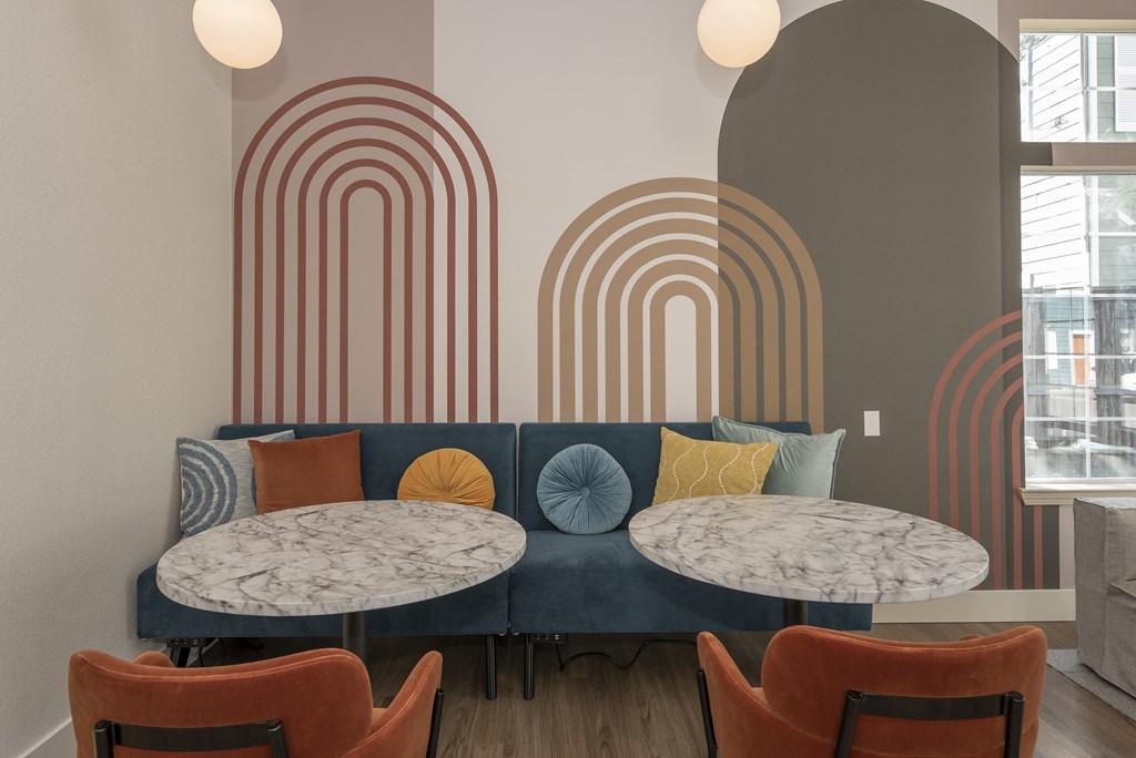 a seating area with three tables and chairs and a wall with art on it