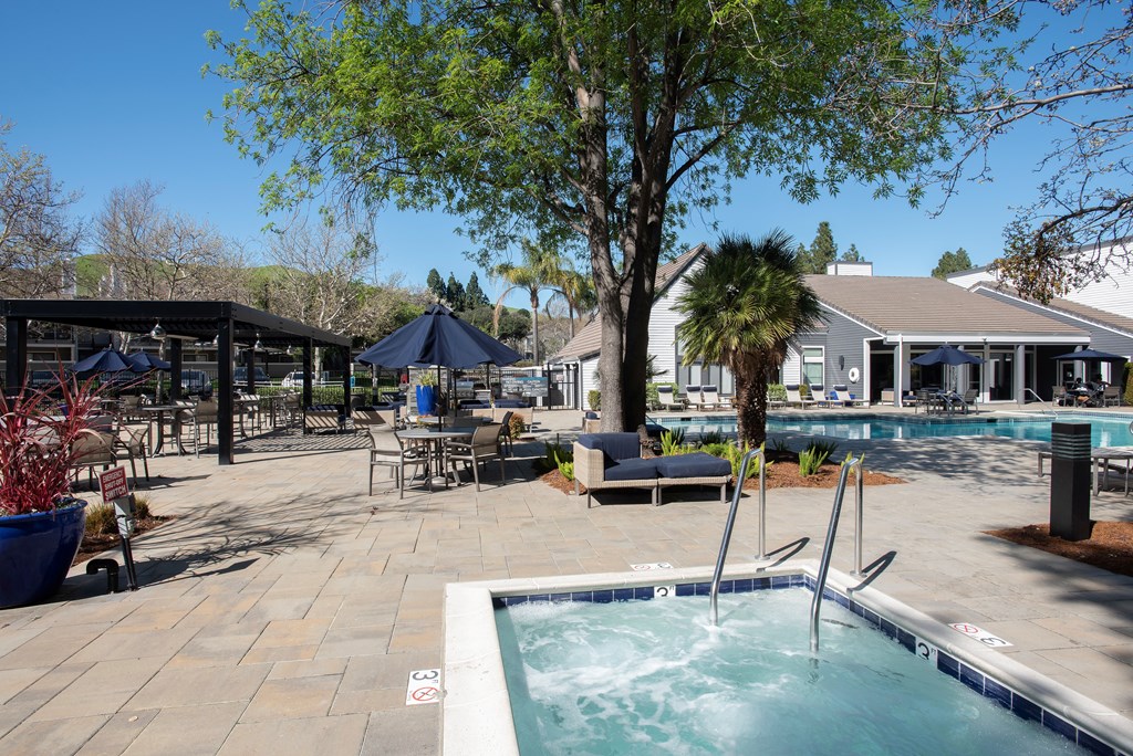 A pool area with a hot tub and a tree at Kirker Creek Apartments, Pittsburg, California