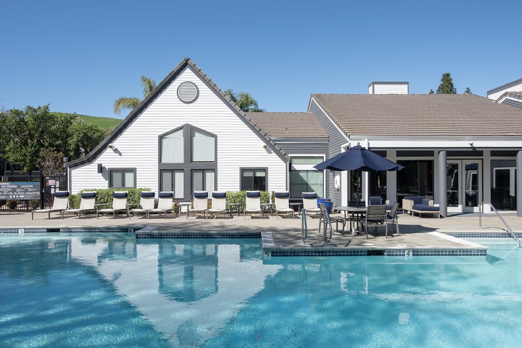 A white house with a pool in front at Kirker Creek Apartments, California