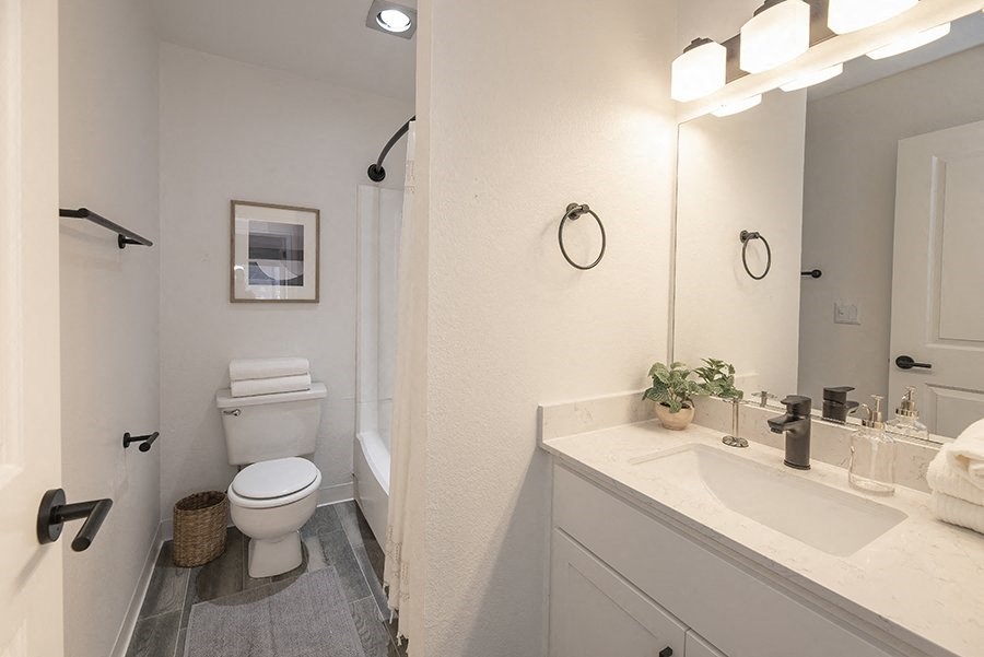 Apartments for Rent Citrus Heights, CA - The Arlo - Bathroom with Wood-Style Flooring, a Vanity, White Cabinets, a White Bathtub, and Stylish Decor