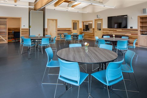 A conference room with a round table surrounded by blue chairs.