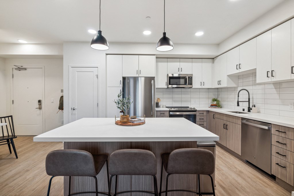 an open kitchen with a large white island with four chairs at 38° NORTH, California