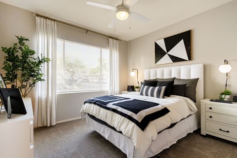 A bedroom with a large bed and a ceiling fan.