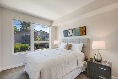 a bedroom with a large window and a large bed