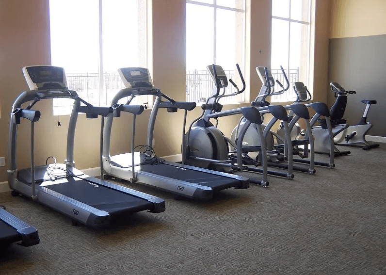 Reno, NV Apartments-Bungalows at Sky Vista-Fitness Center with Large Windows, Carpet Flooring, and Equipment