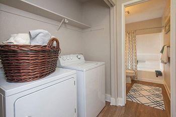 A laundry basket is on top of a washing machine in a small room.