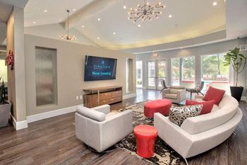 A living room with a couch, ottoman, and a chandelier.