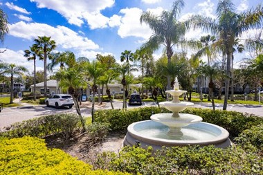 a fountain in a parking lot with palm trees in the background
