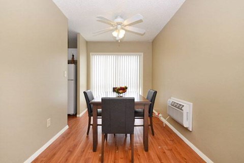 A dining room with a table and chairs and a ceiling fan.