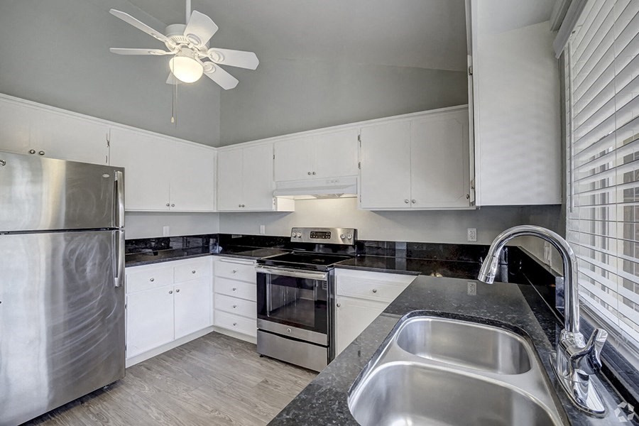 a kitchen with white cabinets and black countertops