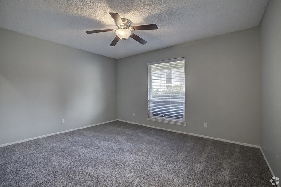 an empty room with a ceiling fan and a window