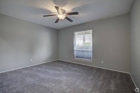 an empty room with a ceiling fan and a window