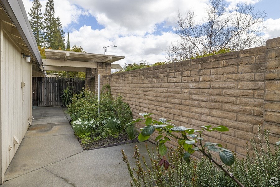 a brick retaining wall with a concrete path in front of it