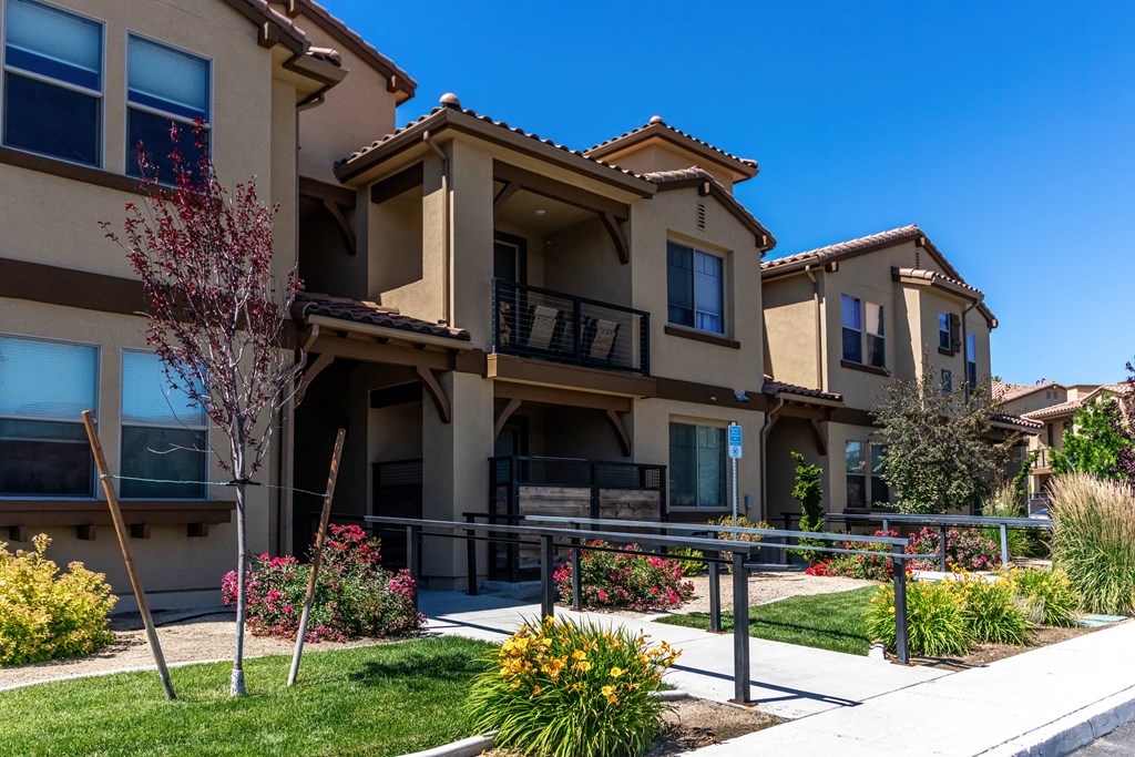 a group of building with a sidewalk in front of them and a blue sky in the background