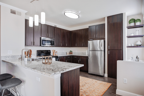 a kitchen with a marble counter top and a stainless steel refrigerator