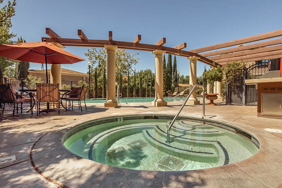 a hot tub with a fountain in the middle of a patio with tables and chairs