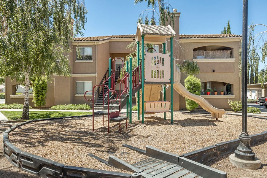 a playground with a slide and swings in front of an apartment building
