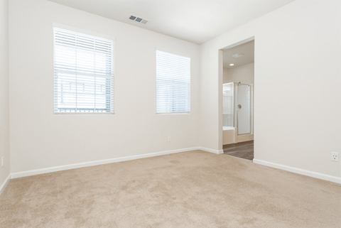 an empty living room with two windows and a carpet