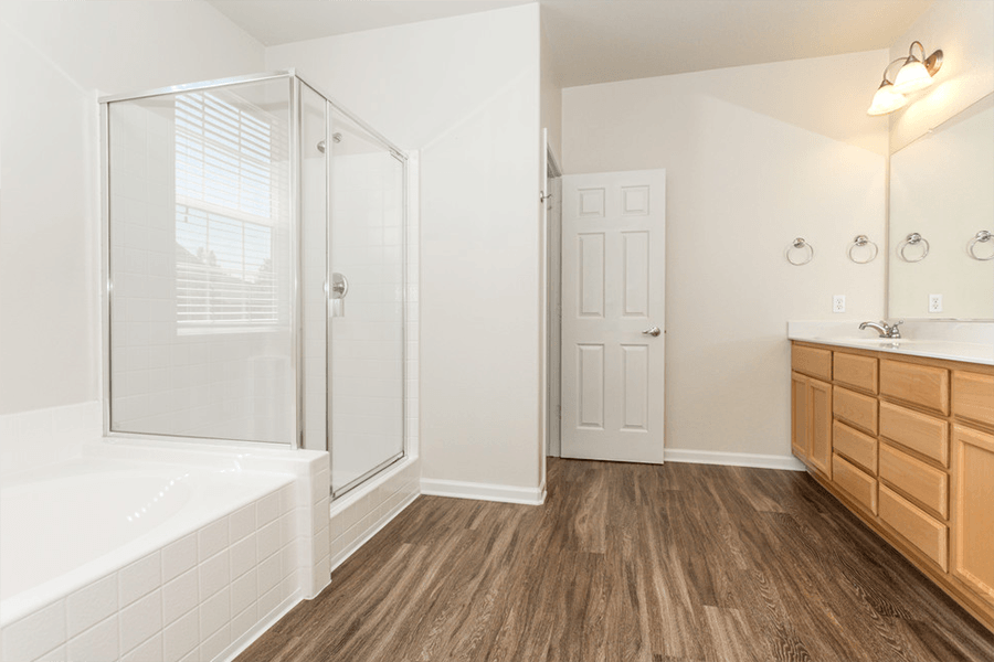 Townhomes In Rocklin California - Large Bathroom With Wood Flooring, Wood Cabinets, Large Mirror, And Seperate Tub And Shower.