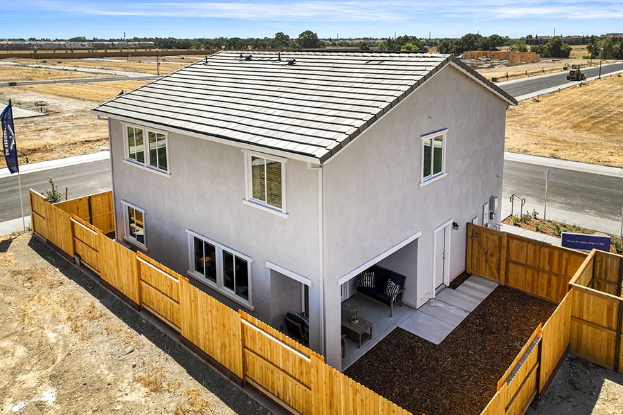 Roseville CA Houses for Rent - Isles - Back View of a Home with Tall Wooden Fence, Patio Under Overhang, and White Window Trim