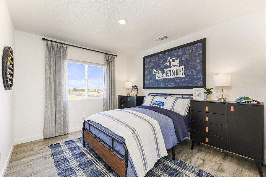Roseville, CA Rental Homes Near Top Golf - Isles - Furnished Bedroom with a Large Window, Hardwood-Style Plank Flooring, and Stylish Decor