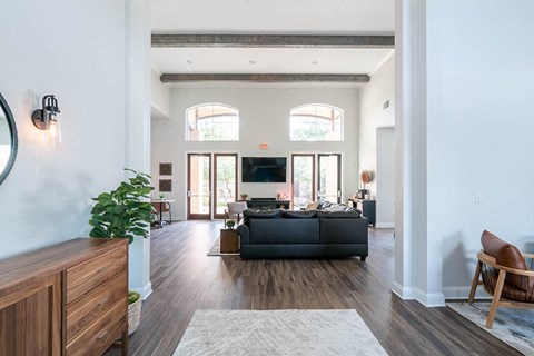A living room with a black couch and a wooden chair.