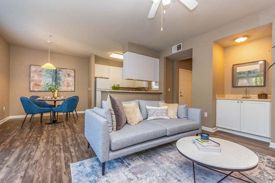 El Dorado Hills Apartments for Rent - Sterling Ranch - Open Layout Living Room with Wood Laminate Flooring, Area Rug, Grey Couch, Round Coffee Table, and Ceiling Fan