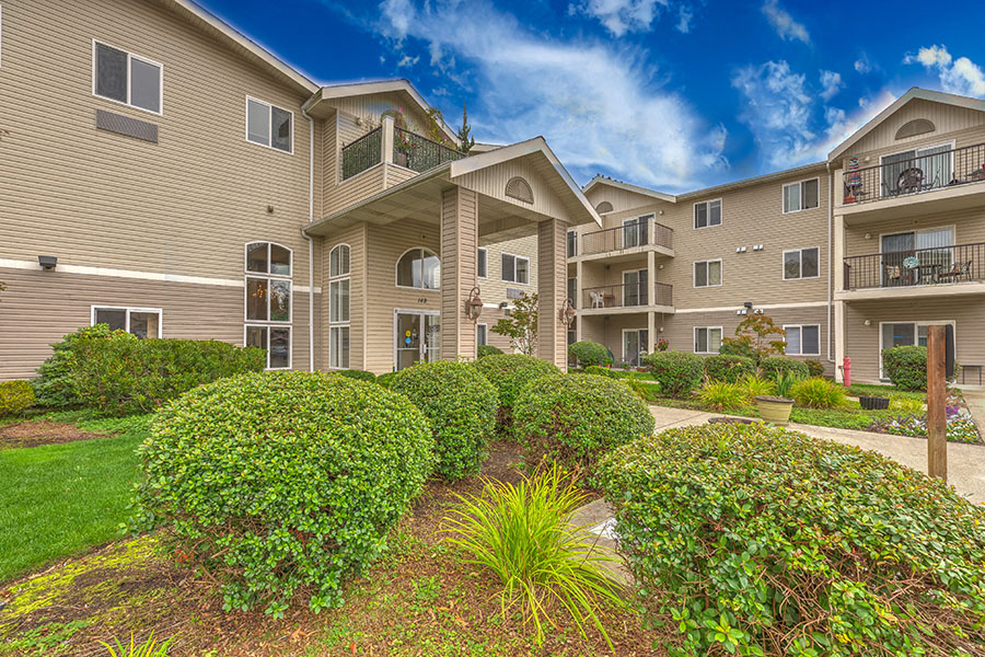 Apartment complex with green bushes in front.