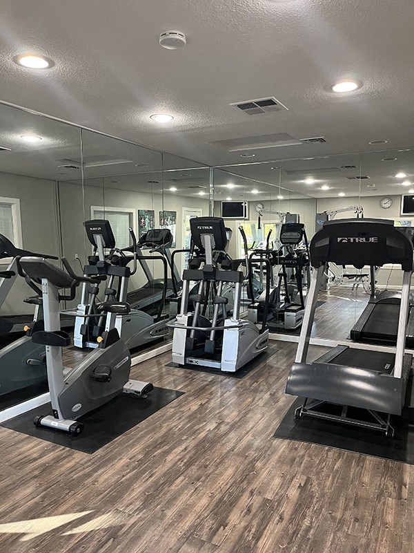 a gym with cardio machines and mirrors