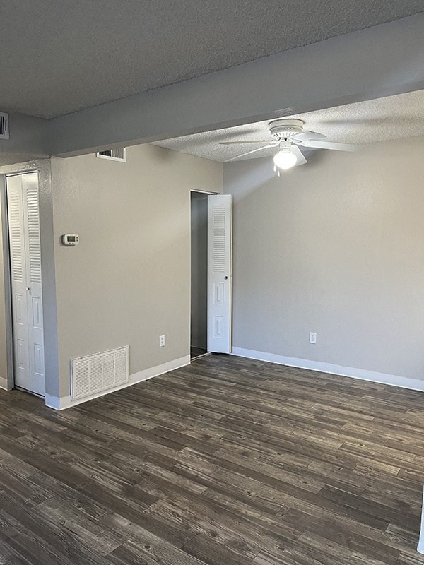an empty living room with a ceiling fan