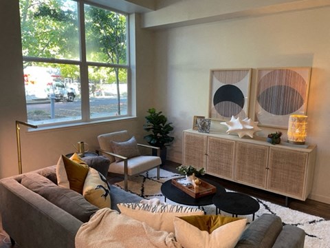A living room with a grey couch, a coffee table, and a large window.