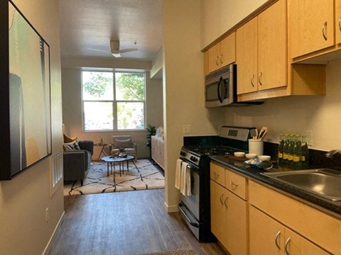 A kitchen with a black stove top oven and black counter tops.