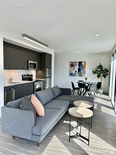 a living room with a couch table and chairs and a kitchen in the background at DOCK 59 APARTMENTS, PORTLAND, OR