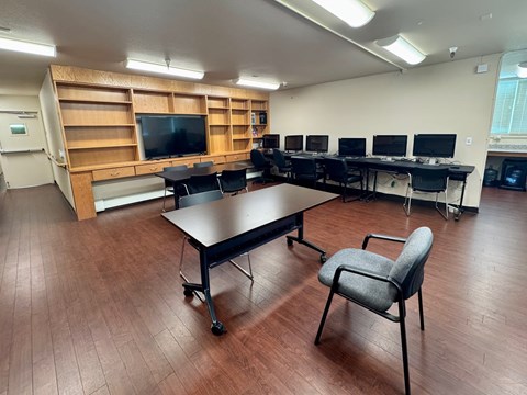 A conference room with a long table, chairs, and a television.