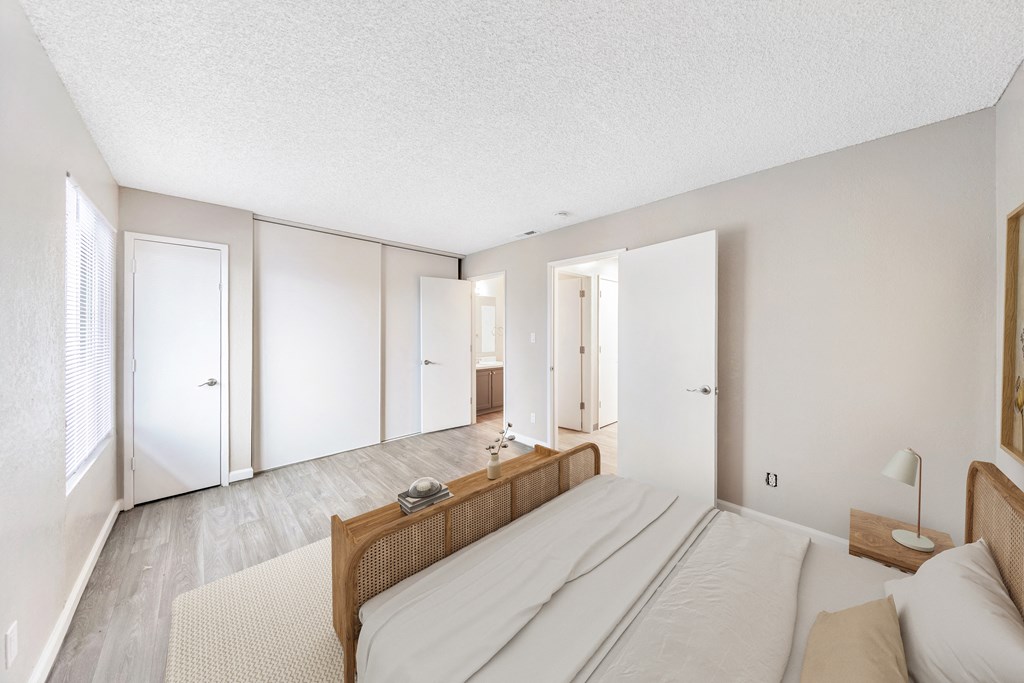 a bedroom with white walls and wood floors