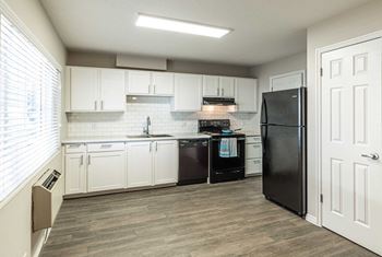 a kitchen with white cabinets and a black refrigerator at Mountain Run Apartments, Orem, Utah