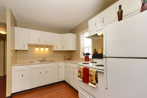 A kitchen with white cabinets and a white refrigerator.