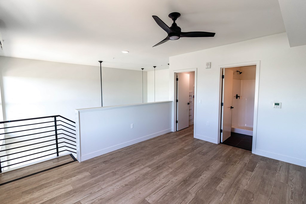 an empty living room with white walls and a ceiling fan