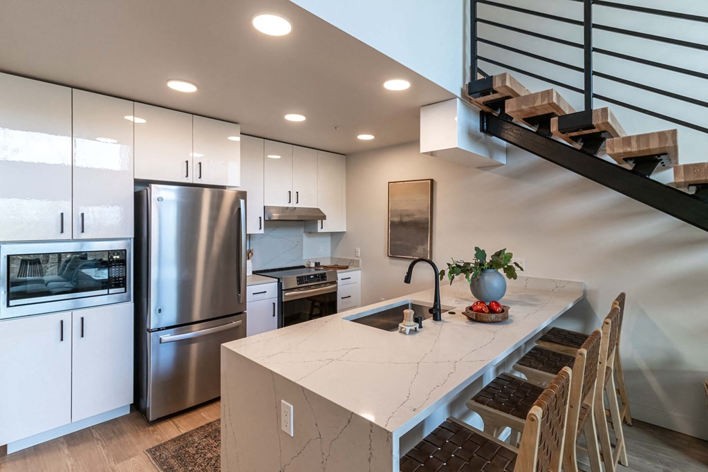 a kitchen with a white counter top and a stainless steel refrigerator