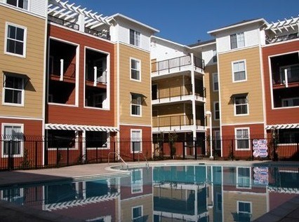 Apartment complex with a pool in front.