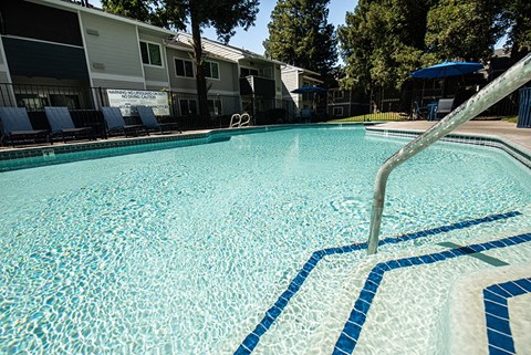 a large swimming pool with chairs and a fence