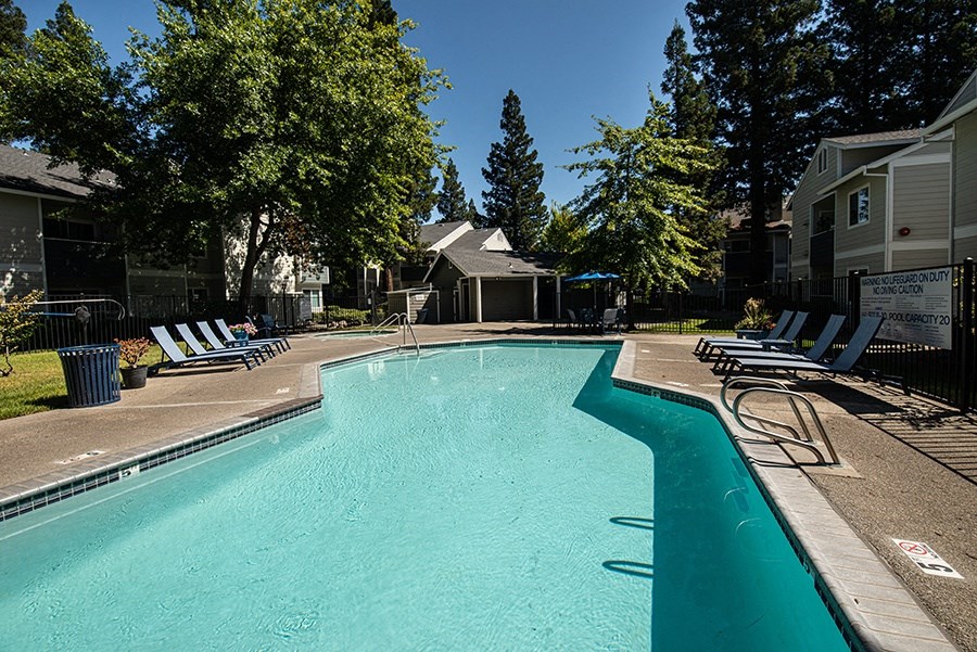 a swimming pool with chairs around it in front of a building