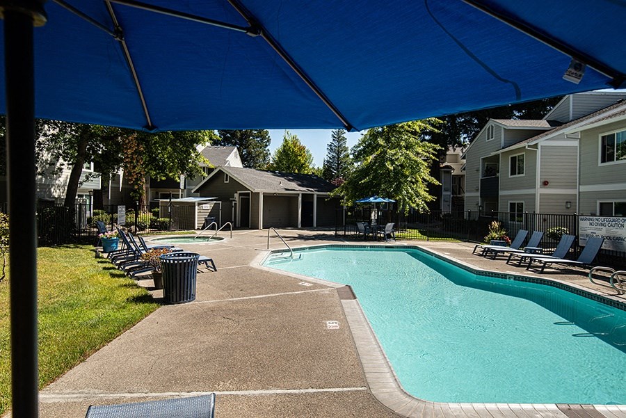 a swimming pool with chairs and a blue umbrella